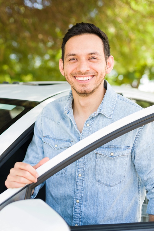 Man smiling entering a car