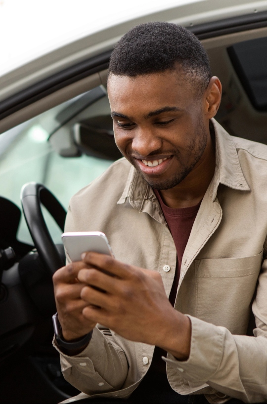 Young man using phone and smiling